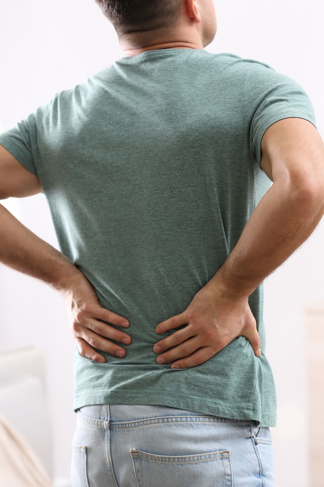 Man experiencing lower back pain, a condition treatable with ARP Wave therapy
